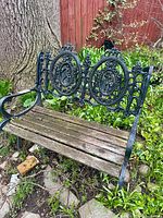 Full view of cast iron and wood garden bench in garden setting