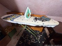 Full view of folding ironing board with both irons on top