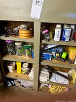 Full view of cupboard shelves with jars of fasteners, wooden bowls, electrical cord, flashlight and solvent cans