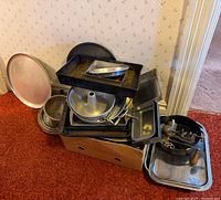 Stacked assortment of pans, colander, tray and meat grinder in box