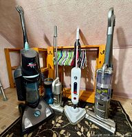 All four floor cleaners standing side by side on rug