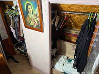 Closet with multiple garments on hangers and trunk below