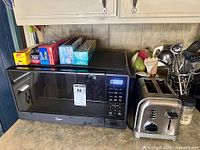 Overall view showing microwave, toaster, storage wrap boxes and utensil caddy