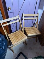 Both wooden folding chairs standing unfolded