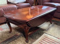 Full view of wood oval drop leaf coffee table with leaves raised