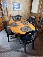 Full view of oval solid wood dining table with four black wooden chairs around it