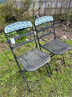 pair of black steel folding chairs on lawn
