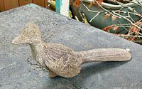 Left side view of entire bird statue on surface