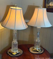 Pair of clear cut crystal lamps on table showing full view with shades