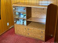 Full view of wood display cabinet showing glass door section, open shelf, lower drawers and cabinet door
