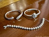 All three sterling silver bracelets on tabletop