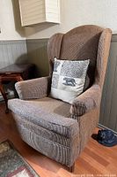 Front view of brown corduroy wingback chair with pillow