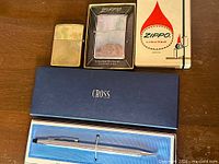 Group shot of both Zippo lighters, Zippo display case, Cross pen box