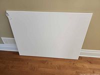 Front view of blank white canvas leaning against wall