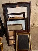 Stack of eleven assorted frames leaning against wall