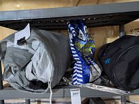 Grey Mercedes-Benz E-Class car cover, blue traction sand bag, black roadside kit bag, reflective blanket visible on shelf