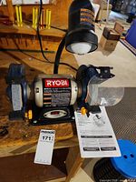 Front view showing Ryobi label, wheels, shields, lamp, manual