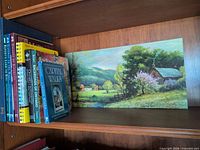 Shelf view showing eight books and the Robert Wood landscape print