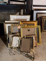 Group shot of all brass-tone frames and two stands stacked against wall