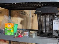 Overall lot on shelf showing bug zapper, Off coils, citronella candles, lighters