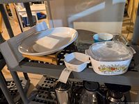 Shelf showing all items: Corning Ware casseroles, Italian platter, Pyrex dish, Pyrex bowl