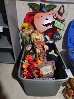 Overview of tote showing metal pumpkin wall piece, scarecrow, garland, wood sign, metal yard sign