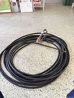 Coiled black hose with sprinkler and spray wand visible