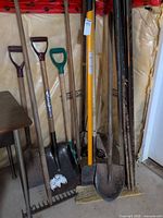 Group of long-handled tools and T-posts leaning against wall