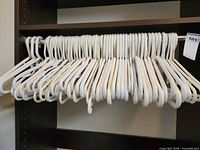 Row of white plastic hangers on closet rod