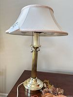 Full view of gold tone lamp with shade and decor items at base
