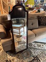 Front view showing full mirror, dark wood frame, arched top