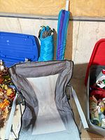 Front view of grey folding chair, umbrella and tent sleeves visible behind