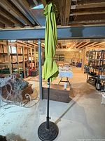 Closed green patio umbrella mounted in base