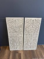 Front view of both carved panels leaning against wall