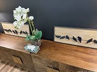 Two CBK wood wall panels displayed on cabinet under black wall