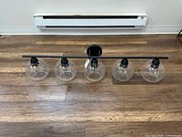 Full view of five-light wall sconce lying on floor, shows overall design