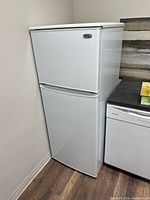 Front view of white Danby DFF9109W apartment refrigerator beside dishwasher