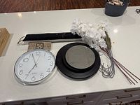 All items arranged on countertop: clock, mirror, florals, fabric sign, wooden sign, hooks