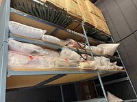 Shelved lot showing pillow inserts, decorative pillows, linens, boxes above