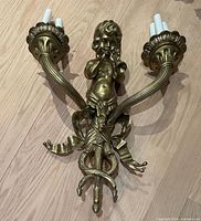Front view of gilt brass cherub wall sconce showing overall design