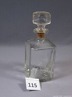 Full view of clear square glass decanter with stopper and lot tag 115 visible