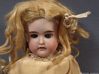 Close frontal view of Armand Marseille bisque doll showing face, wig, and upper dress