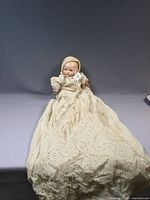Full view of doll wearing long eyelet gown and bonnet