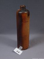 Full view of brown salt-glazed stoneware bottle with embossed Erven Lucas Bols mark and narrow mouth
