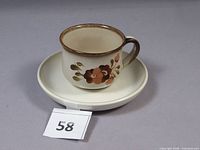 Cup on saucer, pattern and form visible with lot number tag