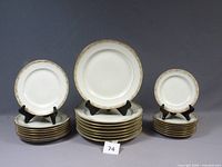 Three stacks of Limoges plates: dinner, salad, bread, each with displayed sample showing floral rim and gold trim