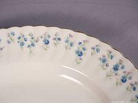 Close-up of rim showing blue forget-me-not pattern and gold trim
