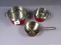 All three red pots with one glass and one stainless lid visible