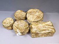 Group of five gold floral fabric china storage cases, four round and one rectangular