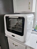 Front view of dishwasher on countertop showing brand and control panel